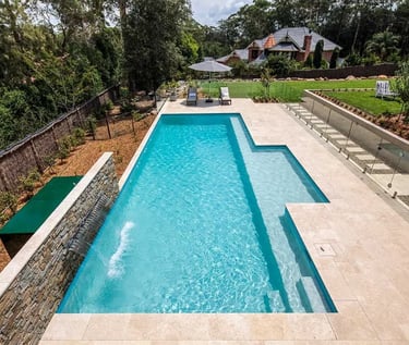 Geometric lap pool with stepped entry, clear turquoise water and pale stone tiling.
