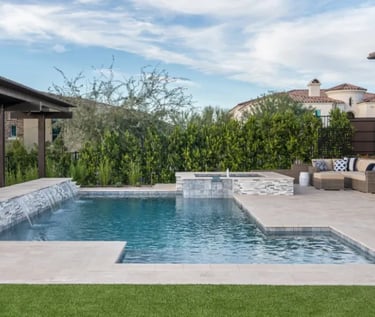 Modern stepped pool with light blue water and pale stone tiling, featuring a waterfall edge