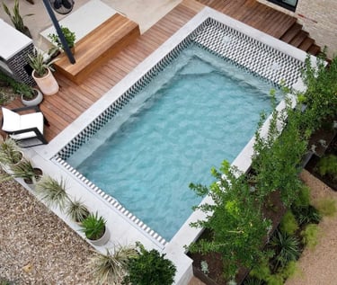 Modern rectangular pool with soft aqua water and patterned grey mosaic tiles