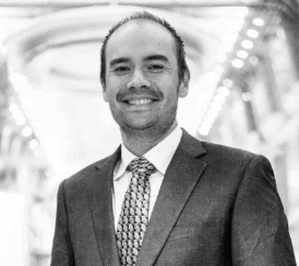 a man in a suit and tie smiling for the camera