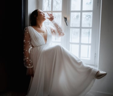 La mariée buvant un verre de champagne au bord d'une fenêtre au domaine de Lamartine