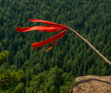 Red survival flag waving on long stick against mountain forest backdrop