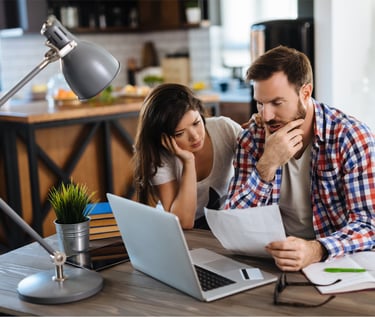 Casal  trabalhando junto ao notebook, com semblante frustrado por não estar conseguindo resultados