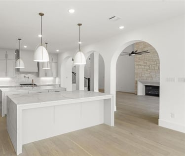 a kitchen with a marble counter top and a large island showing the ac grilles in the ceiling