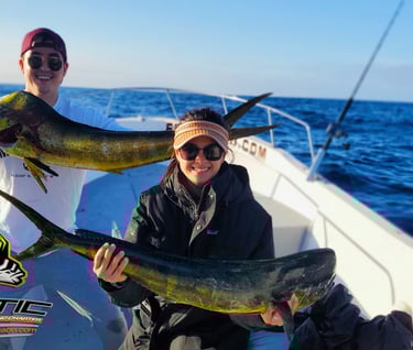 a man and woman holding two fish on a boat