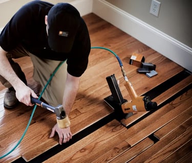 Hardwood floors installer installing prefinished hardwood using air nailer.