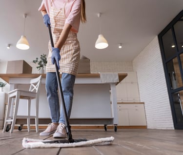 a woman in a pink shirt and jeans cleaning a wooden floor