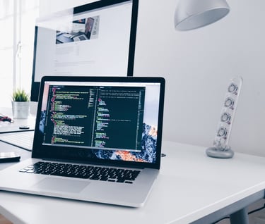 a laptop computer sitting on a desk with a monitor and a keyboard