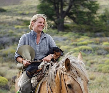A person on horseback holding a small dog.