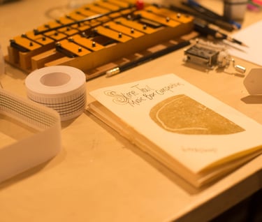 a table with a glockenspiel and a zine about music box composition