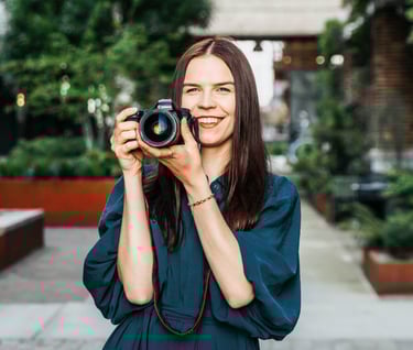 Smiling photographer holding a camera, radiating passion for photography