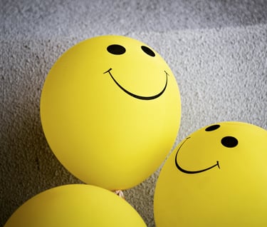 three yellow balloons with smiley faces on them