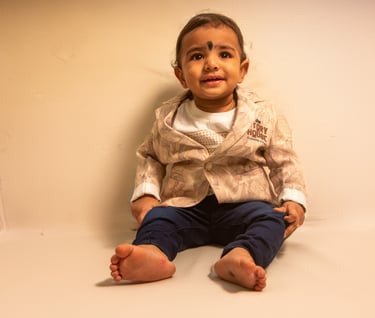 a baby sitting on a white surface with a white background