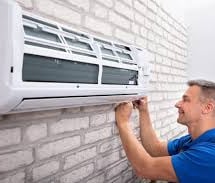 a man in a blue shirt is fixing a window air conditioner