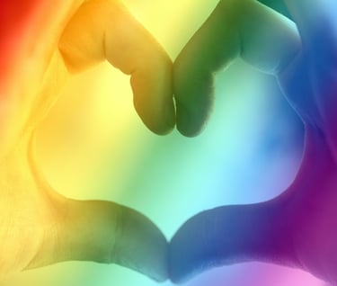 holding hands in a heart shape with a pride rainbow background