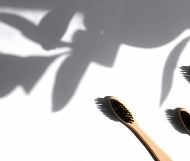 three wooden toothbrushes with a shadow of a plant