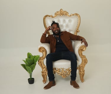 Chevon sitting in a chair with a plant in front of him