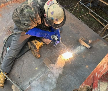 a man in a helmet welding a metal pipe