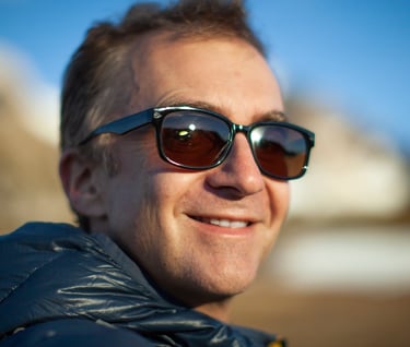 a man in sunglasses and a jacket is smiling