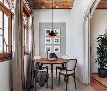 Elegant dining area with rattan and wood chairs and rustic decor elements by SAVIA interior design