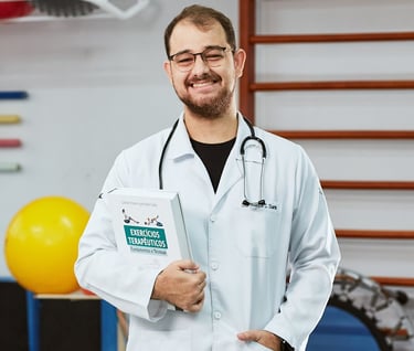 Fisioterapeuta Doutor Luiz Duarte de jaleco branco segurando um livro enquanto sorri