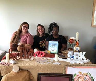 a group of women sitting at a table with doula items around them