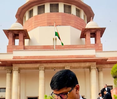 An Advocate in a suit and robe is standing in front of Supreme Court of India