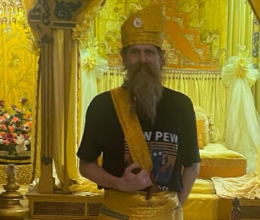 a man at Istana Maimun in traditional Indonesian ceremonial hat and sarong with a kris