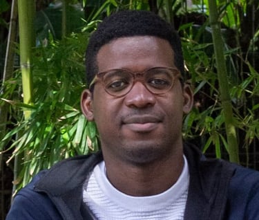 man  with glasses sitting in front of bamboo 