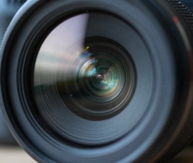 A macro shot of a camera lens reflecting a digital interface. The color palette is dominated by deep ocean slate and sharp mist white highlights.