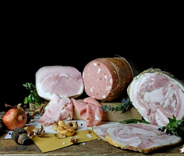Variety of Italian cured meats including mortadella, prosciutto, and porchetta with garnishes.