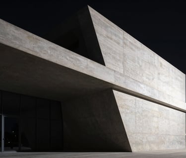A high-contrast cinematic shot of a modern architectural structure at night. Shadows are deep black, with sharp off-white highlights defining the edges of the concrete. Dramatic and sophisticated atmosphere.