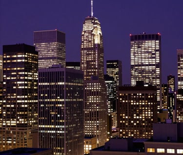 A dramatic nighttime shot of a North American city skyline, buildings glowing with deep purple and off-white lights, representing the vast reach of licensing and media distribution.