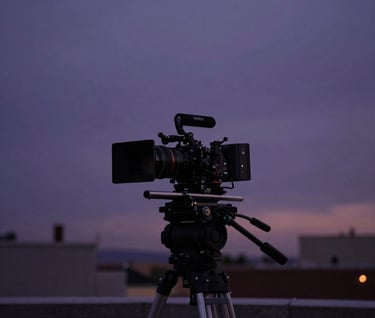 A professional film production setup on a North American rooftop at twilight, featuring a camera rig silhouetted against a deep purple and dark grey sky.