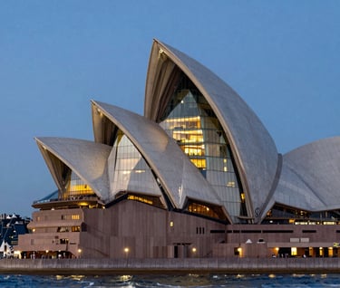 Wide shot of a modern architectural building on the Sydney coastline during the blue hour, glowing off-white interior lights, cinematic composition, elite commercial photography style.