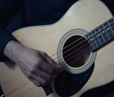 An abstract, artistic photograph capturing the vibration of guitar strings in motion. The lighting is moody and sophisticated, utilizing dark midnight blue tones and a soft off-white glow to highlight the movement.