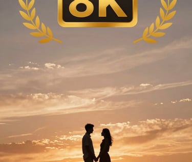 A wide shot of the couple silhouetted against a brilliant sunset. The sky is filled with terracotta and soft sand hues, reflecting a warm and inviting atmosphere.