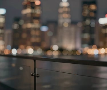 An artistic, out-of-focus cinematic shot of city lights reflecting on a glass surface, incorporating a palette of #3A3F3B and #C1C4BF. It serves as a background texture for the creative concept. Sophisticated and modern.