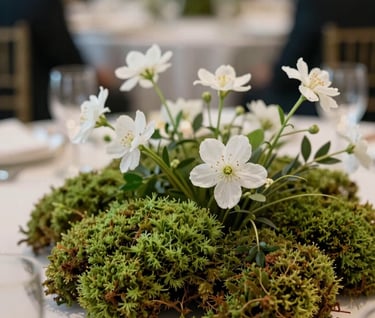 An artistic nature-inspired detail at a high-end event in a North American / US location. A centerpiece featuring Sage Green moss and delicate white flowers, shot with a shallow depth of field to emphasize texture and the organic beauty of the natural world.