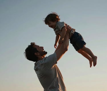 A father lifting a laughing child into the air against a clear evening sky. The low sun creates a soft terracotta rim light on their figures. The style is cinematic, reflecting warmth and refined elegance.