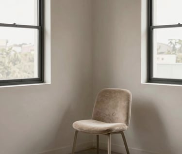 An empty corner of a professional photography studio in South America / Brazil. Minimalist furniture including a single chair in Warm Taupe against a Silver Sand wall. Large windows showing soft natural light, very elegant and clean.