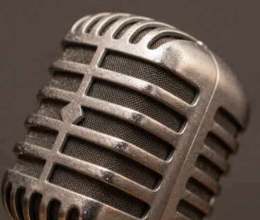 A macro photograph focusing on the textured surface of a vintage microphone. The metallic details glint with muted brown and taupe reflections from the surrounding studio. Sharp focus, sophisticated mood.