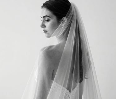 A minimalist black and white photograph of an elopement veil caught in a gentle breeze against a stark white wall. Sophisticated and high-end composition in a North American setting, emphasizing clean lines and texture.