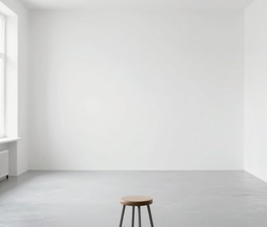 An wide-angle shot of a photography studio with white walls and a grey floor. Minimalist equipment, a single stool in the center, bright and clean aesthetic, emphasizing the professional space of Thais Marçal.