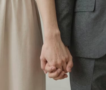 Detail shot of a couple's hands intertwined, focusing on the connection and texture of the fabrics in soft beige #E0DCD9 and dark gray #3D3A38, minimalist and intimate.