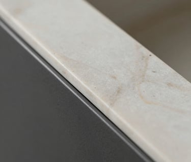 Close-up macro photography of architectural textures. Off-white marble meeting a matte Charcoal metal surface. Precision craftsmanship, minimalist aesthetic, soft diffused lighting.