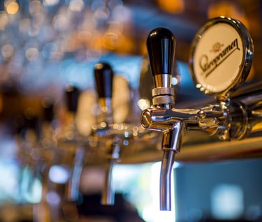 a row of beer taps with a beer on a bar