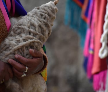 las manos de una artesana sosteniendo una madeja de lana sin hilar