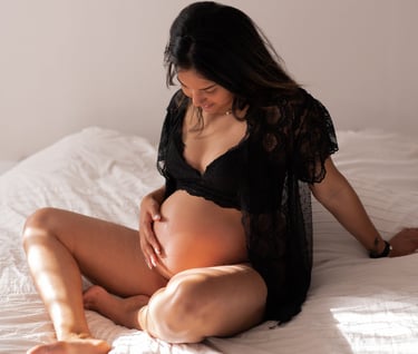 une femme enceinte en sous vêtements noirs assise sur un lit