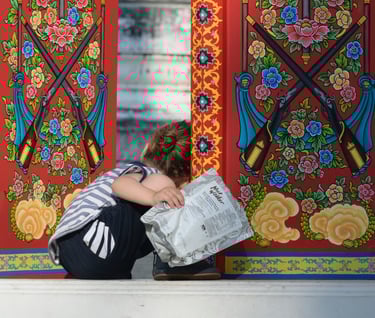 un enfant curieux regarde derrière une porte ouverte dans un temple en Thaïlande 